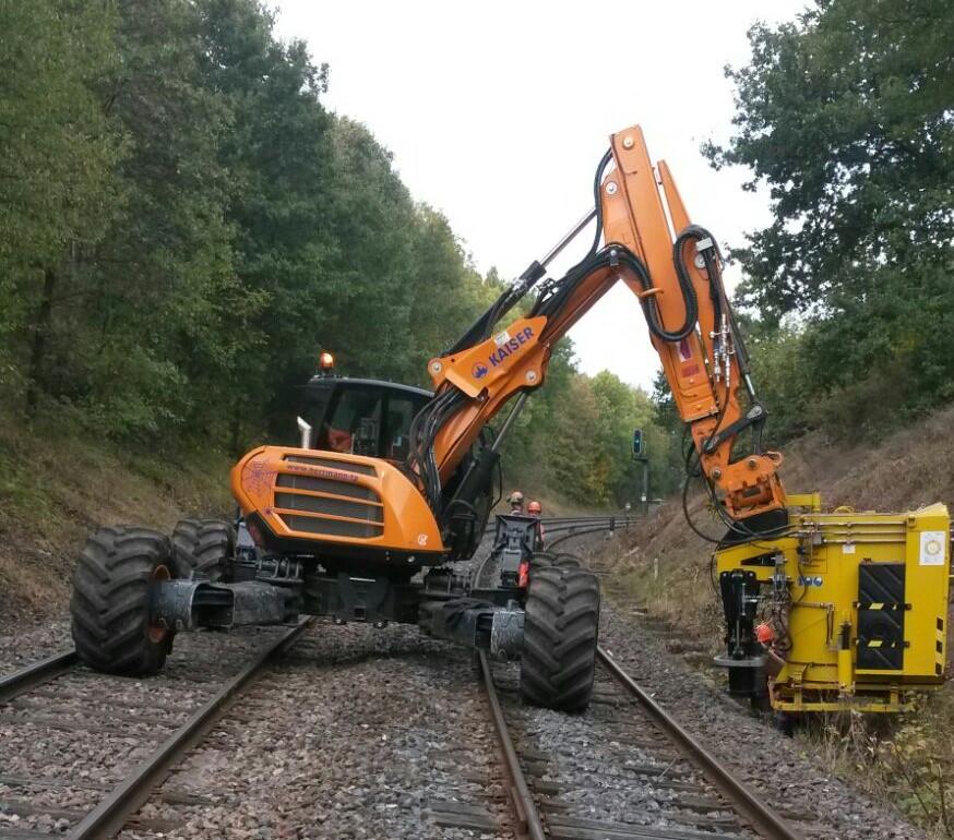 Heavy excavator deployed directly on active railway corridor for mechanized maintenance